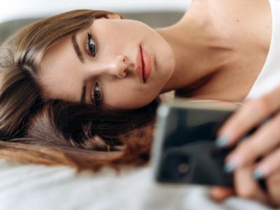 romantic woman looking at mobile phone while laying